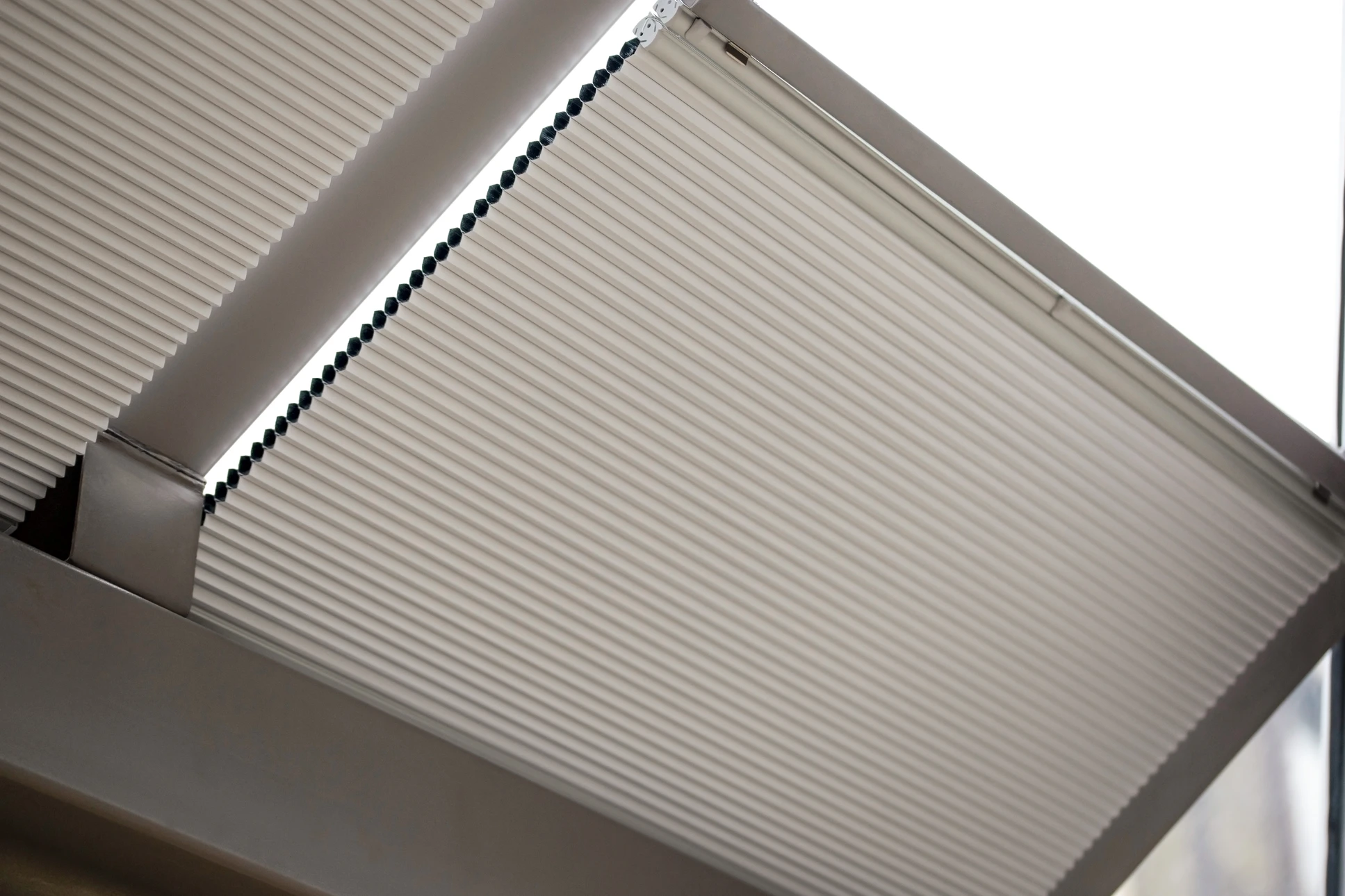 Photographie en intérieur d'une fenêtre de toit Vélux moderne installée dans un plafond en pente, capturant la lumière naturelle qui entre généreusement dans la pièce. La fenêtre est clairement visible et proéminente dans le cadre, montrant son design élégant et ses mécanismes de qualité. Le reste de la pièce montre un intérieur résidentiel contemporain bien aménagé. L'image doit communiquer l'excellence technique et l'intégration harmonieuse d'une fenêtre de toit de qualité dans un habitat moderne.